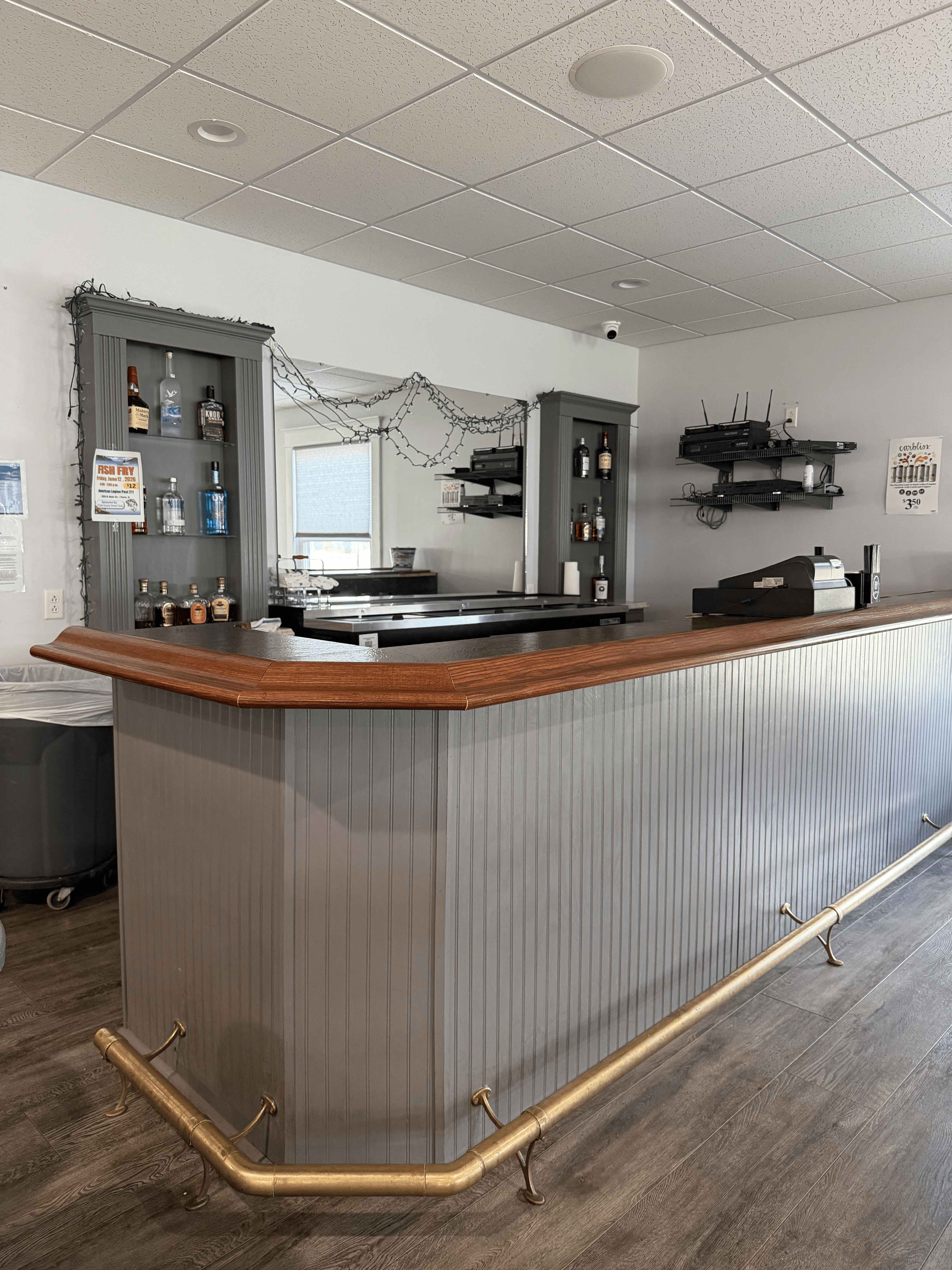 On-site bar with a wood-topped counter, brass foot rail, and mirrored back shelving
