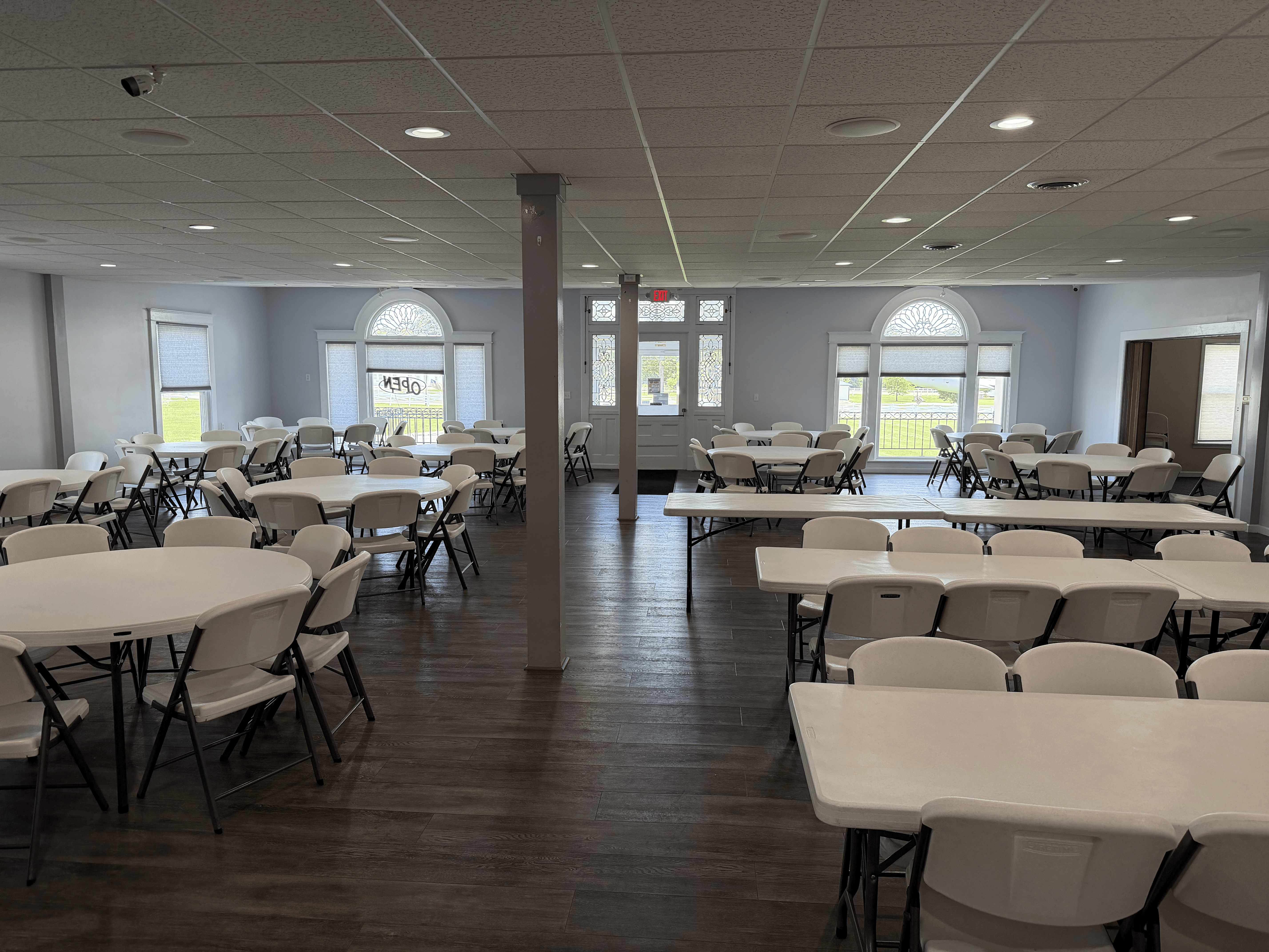 Event hall with a mix of round and rectangular tables and stained-glass entry doors